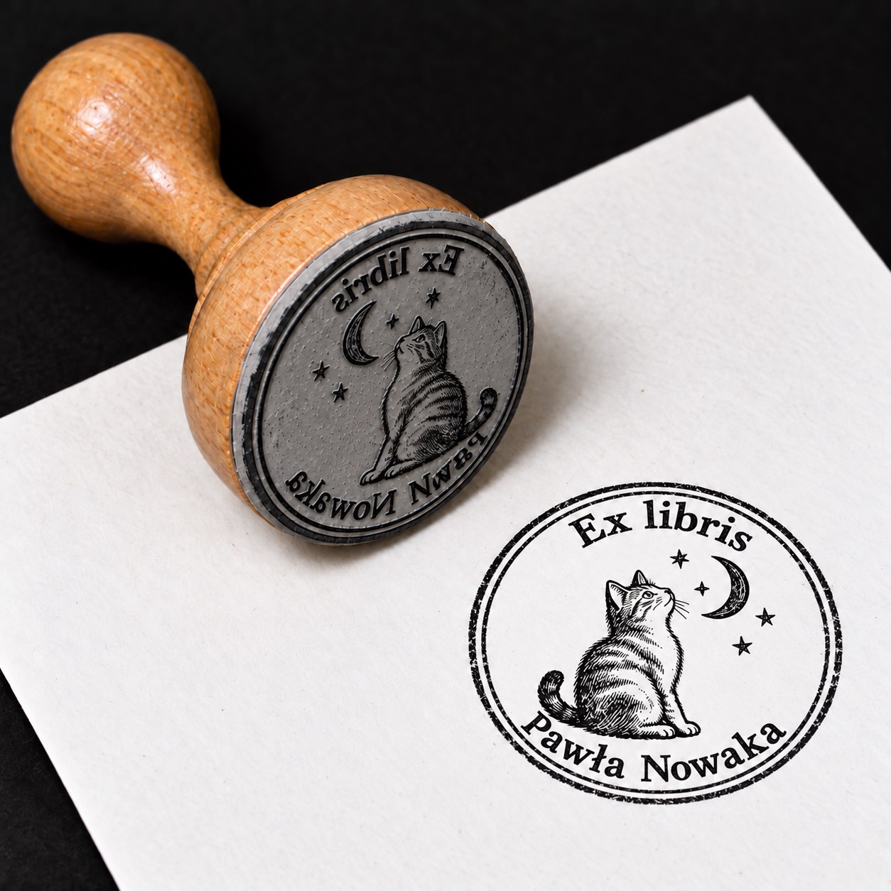 Wizualizacja drewnianej pieczątki ex libris „Kot pod księżycem” i jej odbitki na białej kartce.