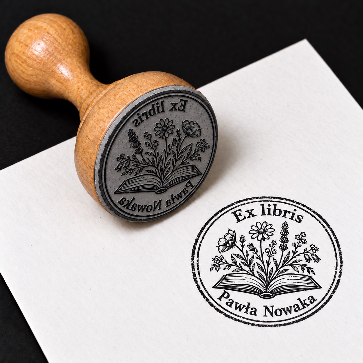Wizualizacja drewnianej pieczątki ex libris „Kwiaty wyrastające z książki” i jej odbitki na białej kartce.